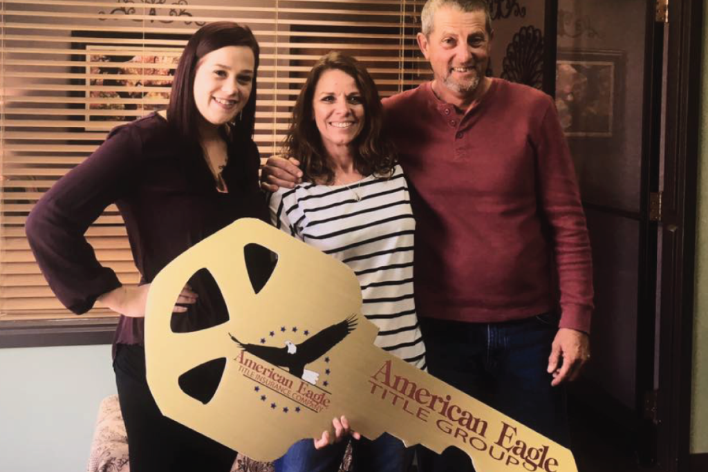 Family holding large key with ae title company on it